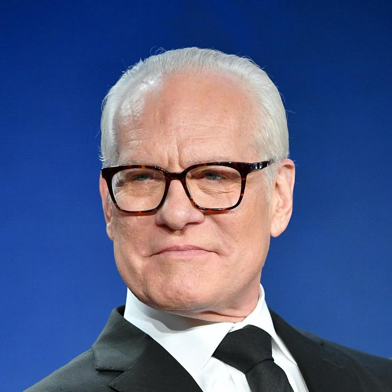 Fashion designer and TV star Tim Gunn looks at the camera in his signature glasses and a suit and tie